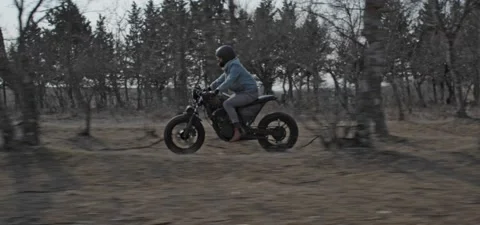 Bearded man rides old cafe racer motorcycle between trees Stock Footage 140626379