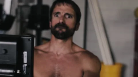 Bearded man rows intensely at gym equipment during workout session Stock Footage 312758975