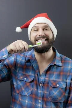 A bearded man in a Santa hat with a wide white-toothed smile Going to brush his Stock Photos