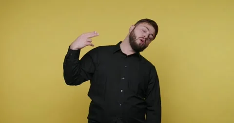 Bearded man showing headshot gesture. Man signs in front of a yellow backgr.. Stock-Footage 326790175