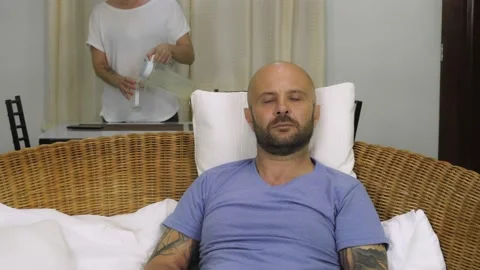 A bearded man sits on the couch and switches TV channels. Vídeo Stock 145315895