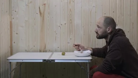 The bearded man sits at the table nods his head and eats Stock Footage 119704081