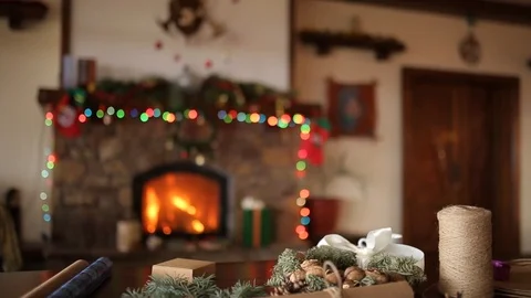 Bearded man sitting and tying a bow on a gifts for New Year near fireplace. Guy Stock Footage 99603979