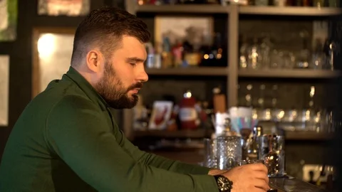 A bearded man is sitting in a bar drinking whiskey and texting on the phone with Stock Footage 126030506