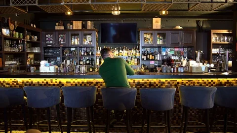A bearded man is sitting in a bar drinking whiskey and texting on the phone with Stock Footage 126370127