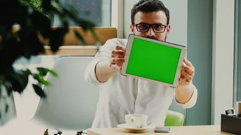 Bearded man sitting in cafe and moving his tablet computer with chromakey to the Stock Footage 112990371