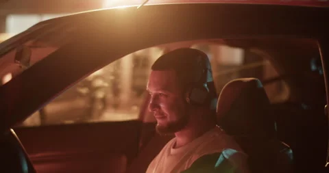 Bearded man sitting in car and putting on headphones Stock Footage 244523830