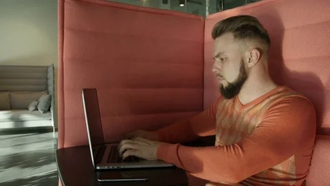 Bearded man sitting on couch with laptop Stock Footage 77282871