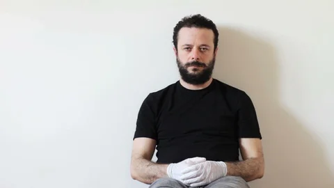 Bearded man is sitting on ground and wearing a gas mask Stock Footage 127572498