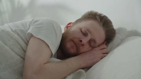 Bearded man sleeping in the bed. Video of european guy covering himself with Stock Footage 233790473