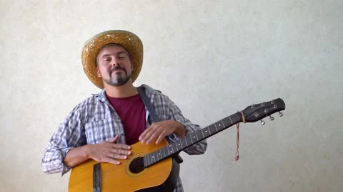 A bearded man with a smile knocks his hands on a guitar 4K Video stock 167998445