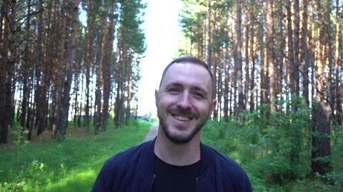 A bearded man smiles while walking in the park. Video stock 156814451