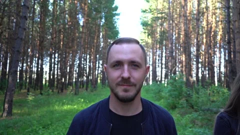 A bearded man smiles while walking in the park. Video stock 158392722