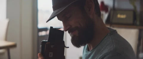 Bearded man smiling and looking through a visor of a vintage camera Stock Footage 202248991