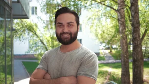 A bearded man smiling at camera in the street with folded arms Stock Footage 141121021