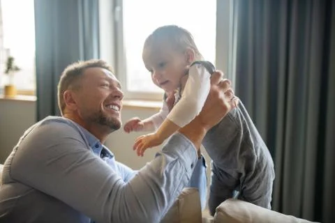 Bearded man smiling while holding his baby daughter Stock Photos
