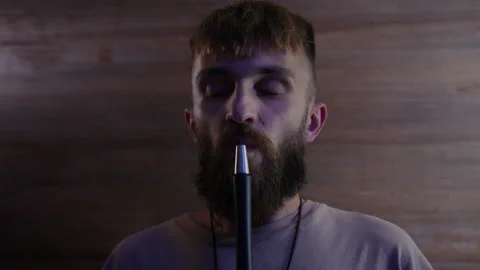A bearded man smokes a hookah and looks at the camera Stock Footage 204843969