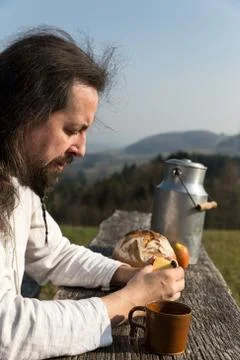 Bearded man is snacking in the nature 库存照片