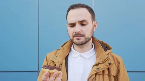Bearded man sniffs a chocolate donut and admires its aroma. Stock Footage 135440231