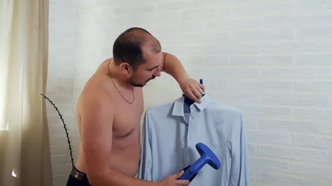 Bearded man soaring, stroking his shirt at home Stock Footage 115721019