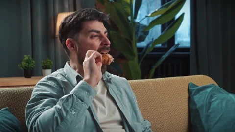 Bearded man spending time at home with fast food delivery, sits on couch Stock Footage 305482187