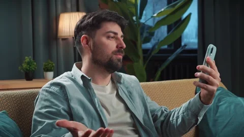 Bearded man spending time at home with fast food delivery, sits on couch talking Stock Footage 305482664