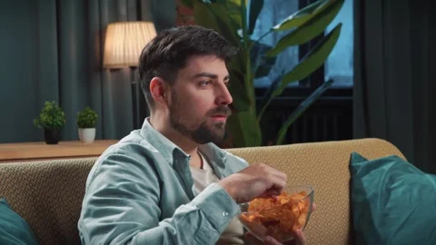 Bearded man spending time at home with fast food delivery, sits on couch Stock Footage 305483157