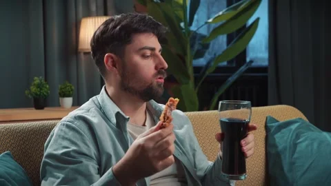 Bearded man spending time at home with fast food delivery, sits on couch Stock Footage 305483177