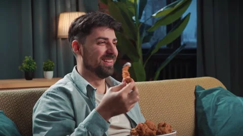 Bearded man spending time at home with fast food delivery, sits on couch Stock Footage 305483926