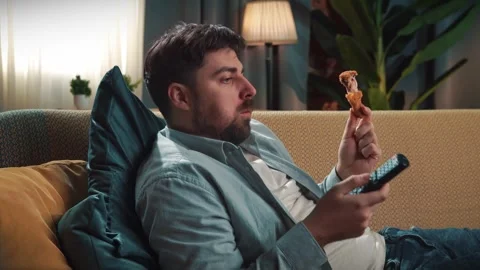 Bearded man spending time at home with fast food delivery, lays on couch Stock Footage 305485557