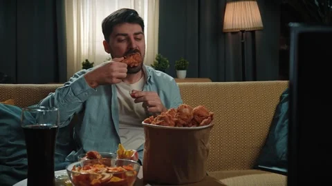 Bearded man spending time at home with fast food delivery, sits on couch Stock Footage 305488831