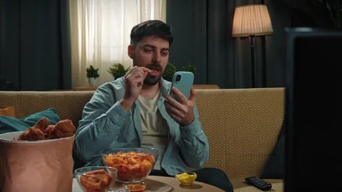 Bearded man spending time at home with fast food delivery, sits on couch Stock Footage 305492688