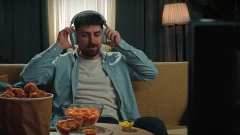 Bearded man spending time at home with fast food delivery, sits on couch Stock Footage 305493400