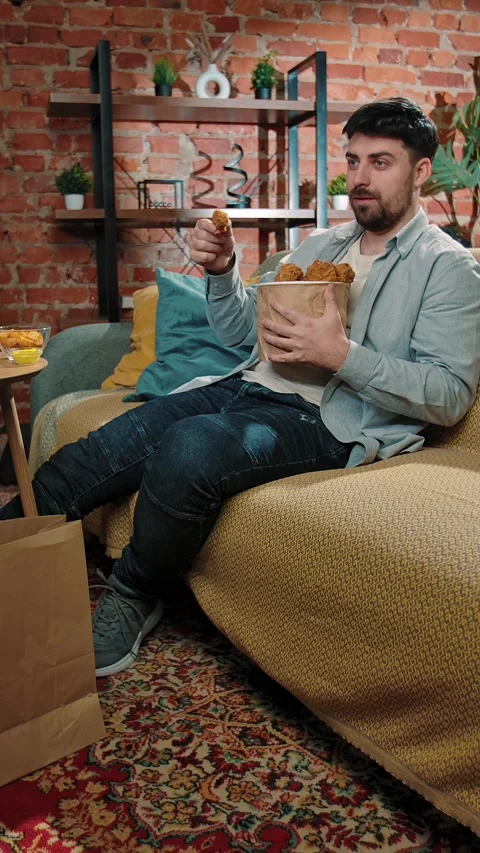 Bearded man spending time at home with fast food delivery, sits on couch Stock Footage 305497490