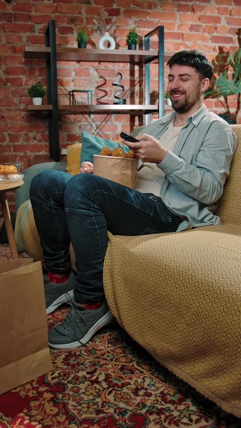 Bearded man spending time at home with fast food delivery, sits on couch Stock Footage 305497769
