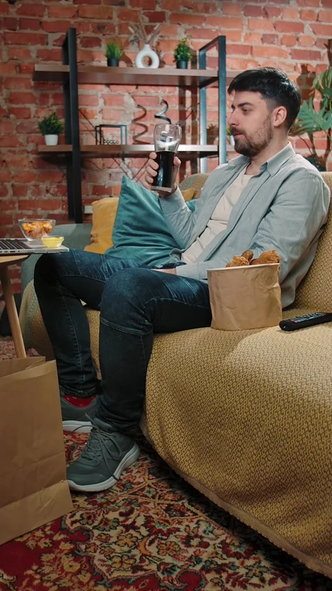Bearded man spending time at home with fast food delivery, sits on couch Stock Footage 305498146