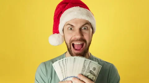 Bearded man with stack of money in christmas hat smiling at yellow background. Video stock 222528781