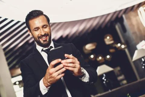 Bearded man standing alone and looking at the screen of his modern smartphone Stock Photos