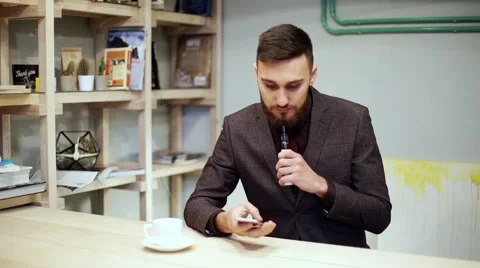 Bearded man in suit is smoking e-cigarette vape, chatting by smart phone Stock Footage 56891566