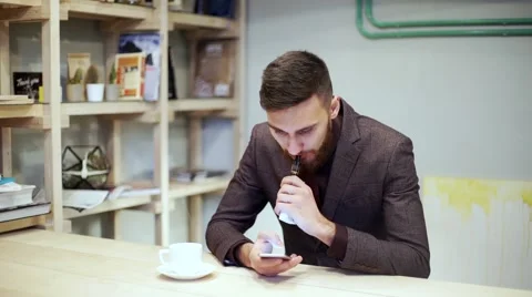 Bearded man in suit is smoking e-cigarette vape, chatting by smart phone Stock Footage 56891602