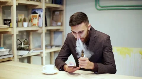 Bearded man in suit is smoking e-cigarette vape, chatting by smart phone Stock Footage 56891620