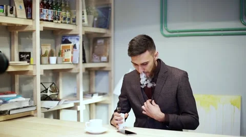 Bearded man in suit is smoking e-cigarette vape, and straight his tie Stock Footage 56891672