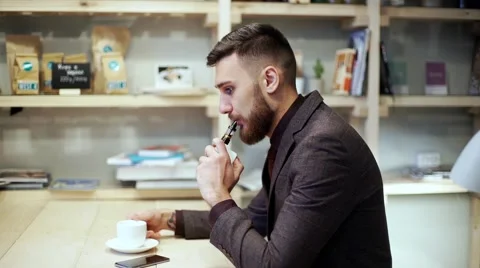 Bearded man in suit is smoking e-cigarette vape, chattingphone and drink coffee Stock Footage 56891728