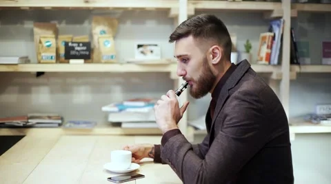 Bearded man in suit is smoking e-cigarette vape, chatting phone and drink coffee Stock Footage 56891761