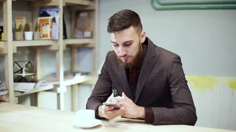 Bearded man in suit is smoking e-cigarette vape, chatting by smart phone Stock Footage 56891782