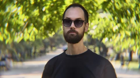Bearded Man in Sunglasses Talking to Camera in Sunlit Park Видео 342824685