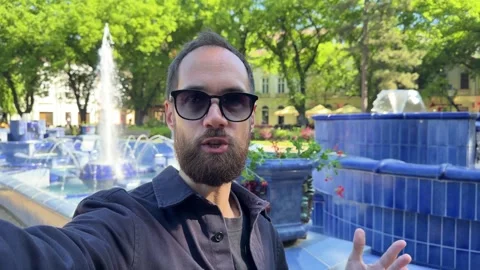Bearded Man in Sunglasses Vlogging by Blue Fountain in Subotica Stock Footage 336178599