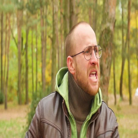 A bearded man in a sweater and leather jacket in the fall Yelling and swearing Stockbeeldmateriaal 69282479