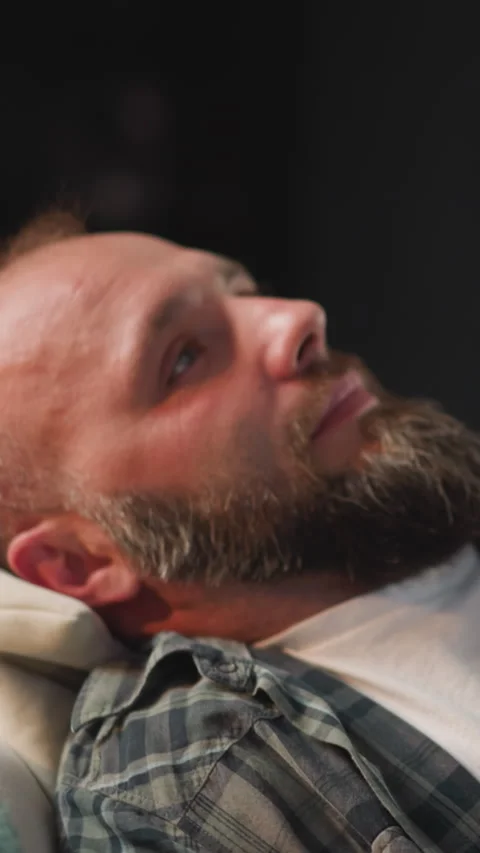 Bearded man takes comfortable pose on sofa to take rest Stock Footage 283290702