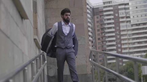 Bearded man takes off jacket walking on city entrance ramp Stock Footage 103935078